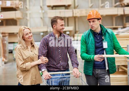 Lustige Unterhaltung von Lagerarbeiter und Kunden, sie reden miteinander, haben Spaß auf dem Markt, Arbeiter helfen Stockfoto