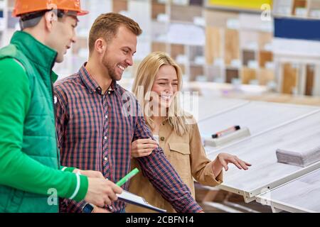 Angenehme Lagerarbeiter froh, Kunden zu helfen, baten sie um Beratung, Arbeiter lieben seinen Job, er ist sozial angepasst Stockfoto