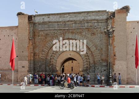 Marrakesch, Marokko-Okt 5,2018:Stadtmauer mit Bab Agnaou Tor und Storchennestern an der Wand, unbekannte Personen, Gruppe von Touristen warten auf eine Tour und Stockfoto
