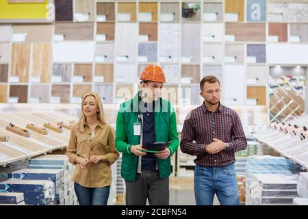 Angenehme Lagerarbeiter froh, Kunden zu helfen, baten sie um Beratung, Arbeiter lieben seinen Job, er ist sozial angepasst Stockfoto