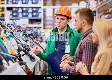 Selbstbewusster kaukasischer Berater in Uniform froh, den Kunden zu helfen, über die Vorteile des Produkts zu sprechen Stockfoto