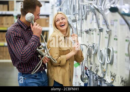 Fröhliche fröhliche Paar lachen, Spaß im Laden neben Dusche Zubehör, reden auf Griff aus der Dusche. Positive Einkaufskonzept Stockfoto