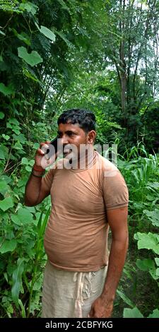 DISTRIKT KATNI, INDIEN - 14. AUGUST 2019: Ein indischer Dorfbauer ruft Handy rund um die Landwirtschaft grünes Feld. Stockfoto