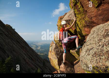 Eine Frau klettert ohne Seil auf den Gipfel des zweiten Flatiron oberhalb von Boulder, Colorado. Stockfoto