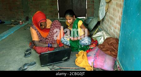 DISTRIKT KATNI, INDIEN - 16. AUGUST 2019: Zwei indische Dorffrauen lernen Laptop-Technologie um armen und schmutzigen Ort zu Hause. Stockfoto