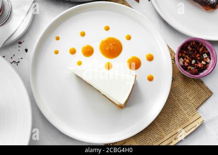 Käsekuchen mit Mango-Sahne auf weißem Tisch Stockfoto