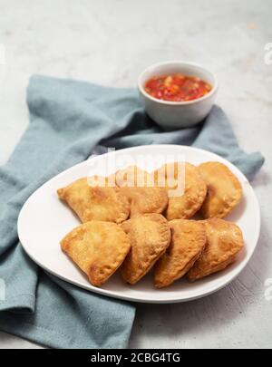 Typische kolumbianische Empanadas werden in der Regel mit würziger Sauce auf Beton serviert Oberfläche Stockfoto