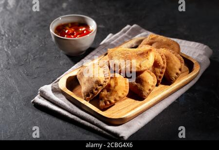 Typische kolumbianische Empanadas werden in der Regel mit würziger Sauce auf schwarzem serviert Hintergrund Stockfoto