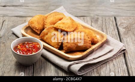 Typisch kolumbianische Empanadas mit würziger Sauce auf Holzoberfläche serviert Stockfoto