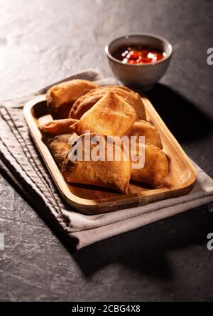 Typisch kolumbianische Empanadas mit würziger Sauce auf schwarzem Hintergrund serviert Stockfoto