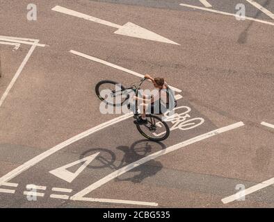 Ein junger Mann auf dem Fahrrad zieht ein Rad entlang der neuen Radtour am Madiera Drive, an der Küste von Brighton, East Sussex, Großbritannien. Stockfoto