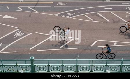 Ein junger Mann auf dem Fahrrad zieht ein Rad entlang der neuen Radtour am Madiera Drive, an der Küste von Brighton, East Sussex, Großbritannien. Stockfoto