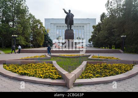 Die Statue von Wladimir Lenin wurde auf der Rückseite des Nationalmuseums in Bischkek, Kirgisistan, aufgestellt. Wladimir Lenin Denkmal mit Blumen herum. Stockfoto