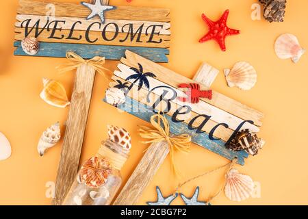 Holzschilder begrüßen Strand, Seesterne und Muscheln auf gelbem Hintergrund. Stockfoto