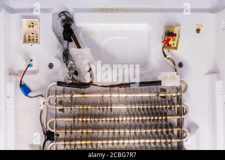 Reparatur des Kühlschranks. Rückwand des Gefrierschranks entfernt. Verdampferspulen mit einem gefrorenen Thermostat. Stockfoto