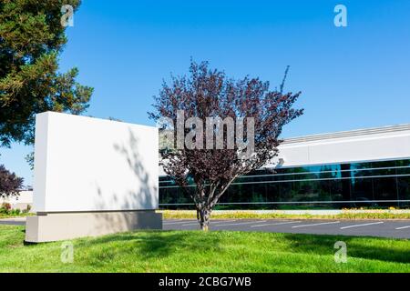 Leere Schilder in der Nähe von ungenutzten flachen Geschäftsgebäude. Leerer Parkplatz. Grünes Gras Rasen Landschaft. Stockfoto