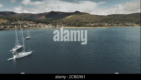 Schottlands Meeresküste Segelboote Luftaufnahme in Küstengewässern in der Nähe von Brodick Dorf, Arran Island. Boote am Wasser in grüner Landschaft. Majestic Sco Stockfoto