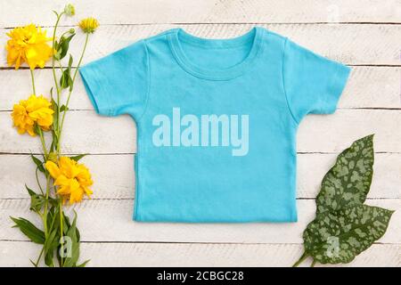 Kinder Shirt Mock Up Bundle, Vorlagen für ersetzen Sie Ihr Design, ein blaues T-Shirt mit Blumenrahmen auf weißem Holzbrett von oben Stockfoto