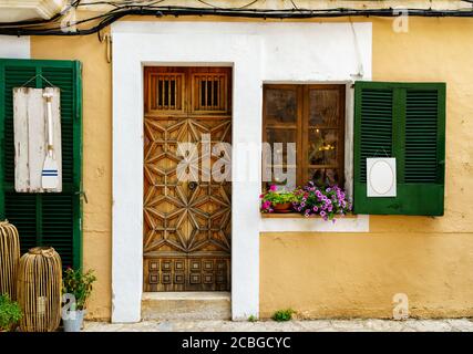 Schöne Hausfassade mit einer beeindruckenden Holztür und Fensterläden mit blanken Schildern zur Dekoration. Mittelmeer Sommer Reise Hintergrund Stockfoto