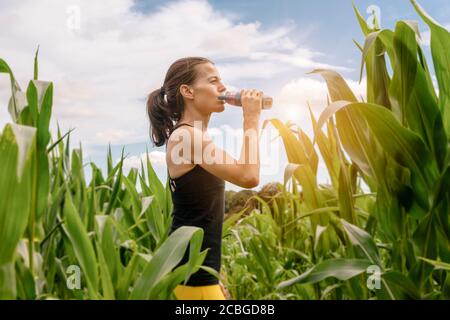 Sportliche Frau trinkt aus einer Wasserflasche, Rehydrierung nach dem Training. Stockfoto