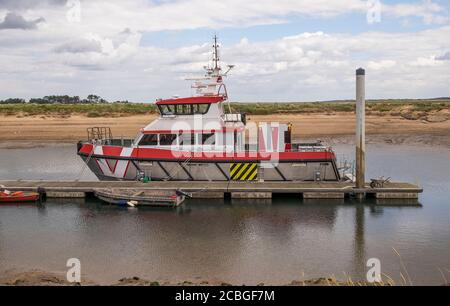 Das Arbeitsboot an der Küste liegt an einem schwimmenden Steg Stockfoto