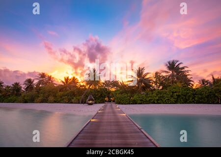 Sonnenuntergang auf der Insel der Malediven, Luxus-Wasservillen-Resort und hölzerner Pier. Schöne Himmel Wolken und Palmen Strand Hintergrund für Sommerurlaub Stockfoto