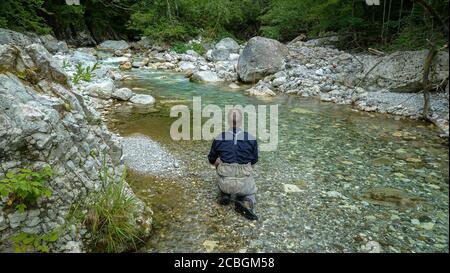 Ein Fliegenfischer, der einen kleinen alpinen Bach fischt, der fließt In den Soca-Fluss in Slowenien Stockfoto