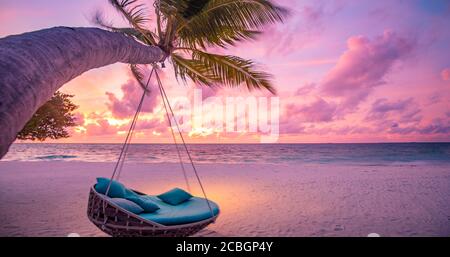 Tropischer Sonnenuntergang Strand Hintergrund als Sommerlandschaft Panorama mit Strand Schaukel oder Hängematte auf Palmen Sand ruhigen Meer Strand Banner. Perfekte Aussicht auf den Strand Stockfoto