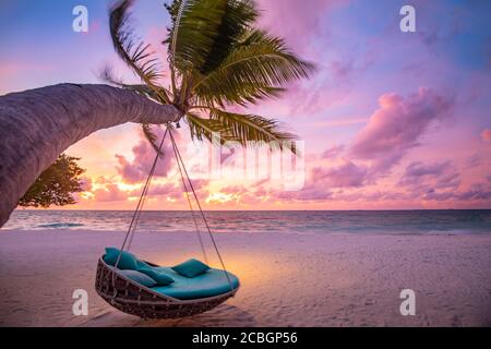 Tropischer Sonnenuntergang Strand Hintergrund als Sommerlandschaft Panorama mit Strand Schaukel oder Hängematte auf Palmen Sand ruhigen Meer Strand Banner. Perfekte Aussicht auf den Strand Stockfoto