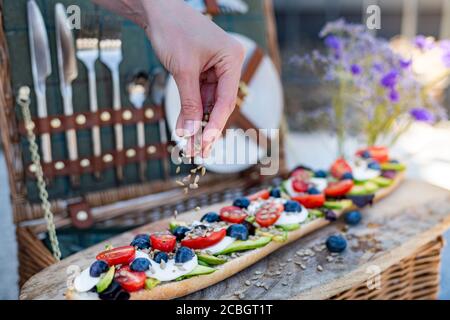 Stilvolles Picknick im Sommer mit Picknickkorb und vegetarischem Baguette mit Avocado, Tomaten und Mozarella-Käse Stockfoto