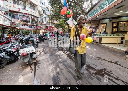 Bhopal, Madhya Pradesh, Indien - März 2019: Ein ehrliches Weitwinkelporträt eines älteren indischen Mannes, der Ballons auf einer schmutzigen Marktstraße in der Altstadt verkauft Stockfoto