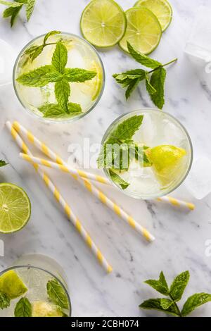 Mojito Cocktail oder Mocktail, traditionelles frisches Getränk mit Limette und Minze. Mit Papierhalmen auf dem Tisch. Draufsicht, von oben. Auf einem weißen Marmortisch Stockfoto