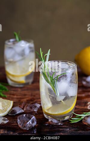 Zitronengetränk mit Rosmarin und Eis. Gin und Tonic, GT. Auf einem rustikalen Holzhintergrund. Erfrischender Cocktail oder Detox Mocktail mit hausgemachten Kräutern. Kopieren Stockfoto