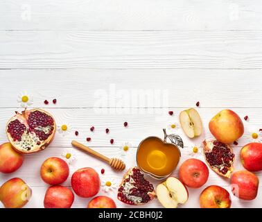 Rosh hashanah (jüdisches Neujahrsfest) Konzept. Traditionelle Symbole. Äpfel, Honig und Granatäpfel auf weißem Holzhintergrund. Stockfoto