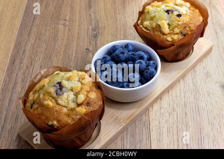 Heidelbeer-Muffins mit Becherbeeren auf Holztisch Stockfoto