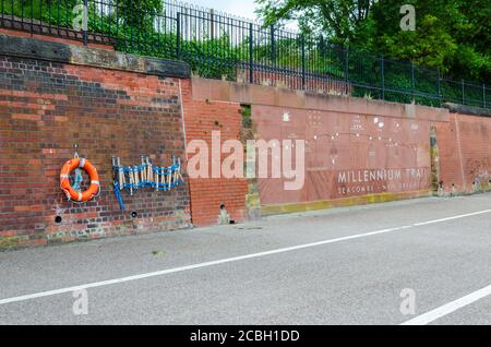 Seacombe, UK: 23. Jun 2020: Architektonische Kunst eines Rettungsrings und einer Fluchtleiter werden an einer roten Ziegelwand neben einem Planogramm des Millennium T befestigt Stockfoto