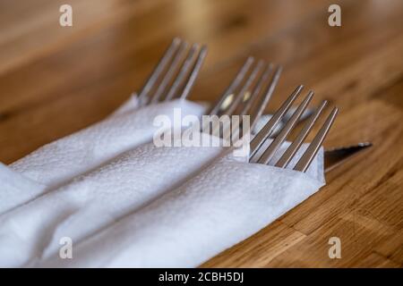 Messer und Gabel in einer Serviette auf einem Holztisch in einem Restaurant eingewickelt. Besteck-Sets. Stockfoto