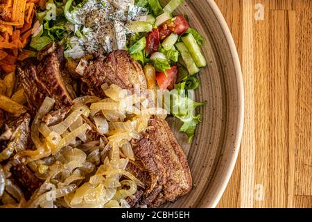 Gegrillte Schweineribs mit gebratenen Zwiebeln und frischem Gemüse auf einem weißen Teller. Draufsicht Stockfoto