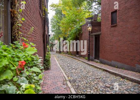 Schmale Gasse mit alten Backsteinhäusern und Gas gesäumt Beleuchtete Lampenpfosten an einem bewölkten Herbsttag Stockfoto