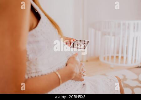 Schwangere Frau, die auf ihre Baby Zwillinge Sonographie. Glückliche werdende Mutter genießt das erste Foto ihrer Kinder, Gesicht ist nicht erkennbar. Stockfoto