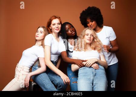 Junge hübsche kaukasische, afro, skandinavische Frau posiert fröhlich zusammen auf braunem Hintergrund, Lifestyle diverse Nationalität Menschen Konzept Stockfoto
