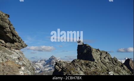 Der Kletterer hat den Gipfel erreicht und steht alleine auf dem Gipfel. Stockfoto