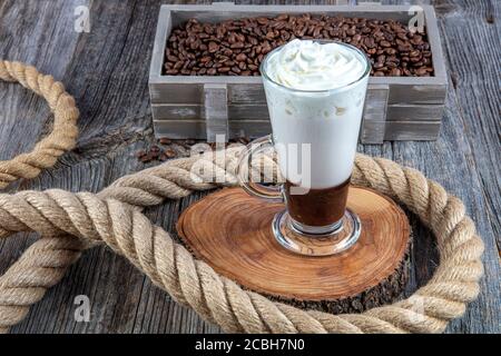 Caffe Mokka mit Schlagsahne. Latte Macchiato in einem hohen Glas. Glas Kaffee Latte und Kaffeebohnen auf dunklem Hintergrund. Сopy Raum Stockfoto