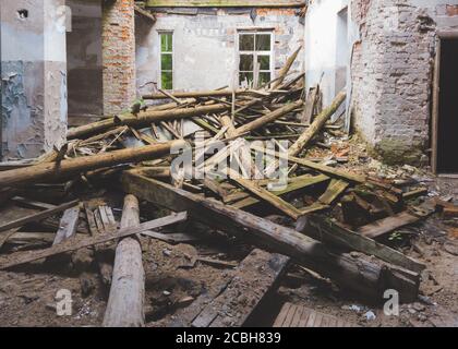 Zerstörte Innenraum des alten verlassenen Gebäude. Holzstämme von gebrochenem Dach. Zerstörtes Haus Stockfoto