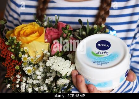 Kind hält ein Glas Nivea Soft Creme und Blumen Stockfoto