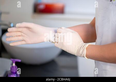 Arzt trägt medizinische Handschuhe im Operationssaal. Nahaufnahme der Hände mit weißen Latexschutzhandschuhe Stockfoto