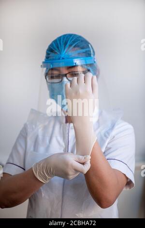 Lady Krankenschwester trägt chirurgische Maske, Gesichtsschutz und OP-Handschuh. Gesundheit und medizinisches Konzept Stockfoto