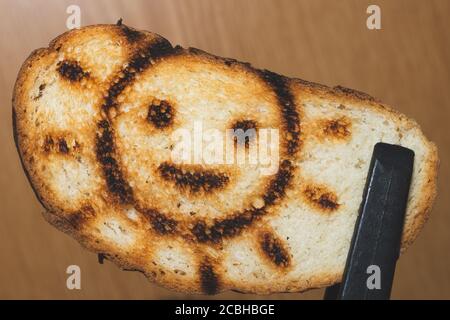 Geröstetes Brot mit lächelndem Sonnenbild. Symbol auf dem Toast Stockfoto