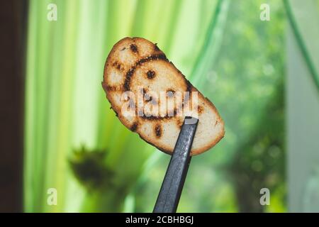 Geröstetes Brot mit lächelndem Sonnenbild. Symbol auf dem Toast Stockfoto