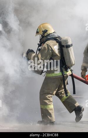 Feuerwehrleute löscht das Feuer aus dem Feuerwehrschlauch, mit Feuerlöschwasserschaumfass mit luftmechanischem Schaum während des Berufsurlaubs Feuerwehrleute Stockfoto